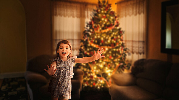 erfreutes Mädchen vor dem Weihnachtsbaum