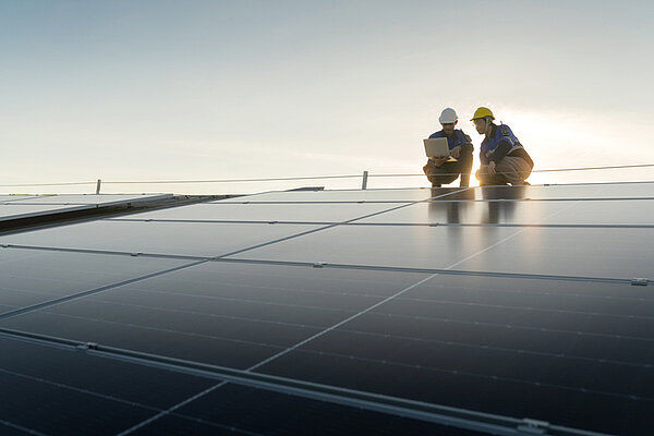 Spezialisierter Techniker professioneller Ingenieur mit Laptop- und Tablet-Wartungsprüfung bei der Installation von Solardach auf dem Werksdach unter Sonnenlicht. Ingenieurteam Vermessung Überprüfen Solarpanel Dach.