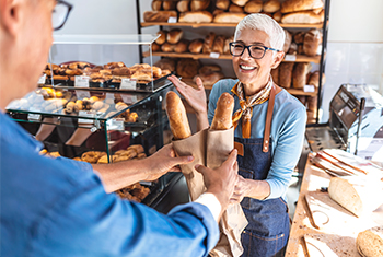 Bäckereiverkäuferin streckt Backwaren entgegen