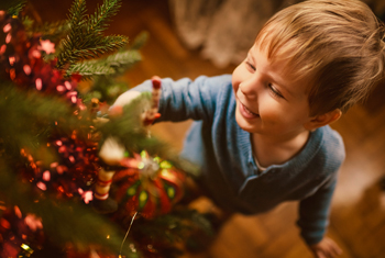 Kleiner Junge glücklich vor Weihnachtsbaum